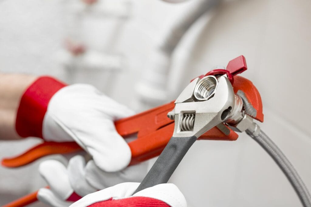 Plumber holding pipe wrenches for an emergency repair in Ontario