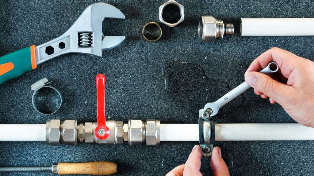 Plumber repairing a pipe valve with an adjustable wrench in Ontario