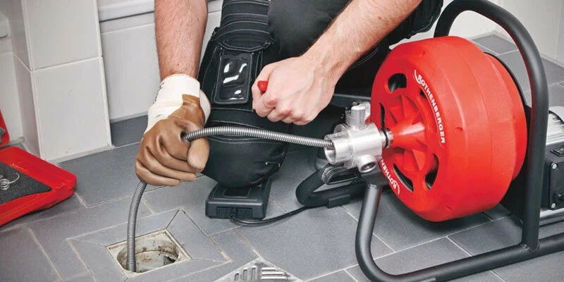Plumber using a drain-cleaning machine in Ontario