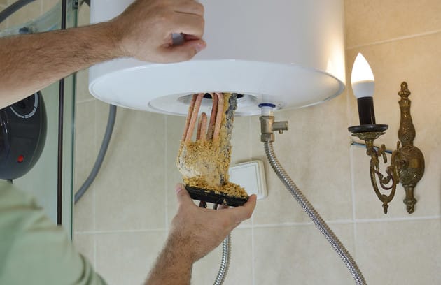 Technician removing mineral buildup from a water heater in Ontario