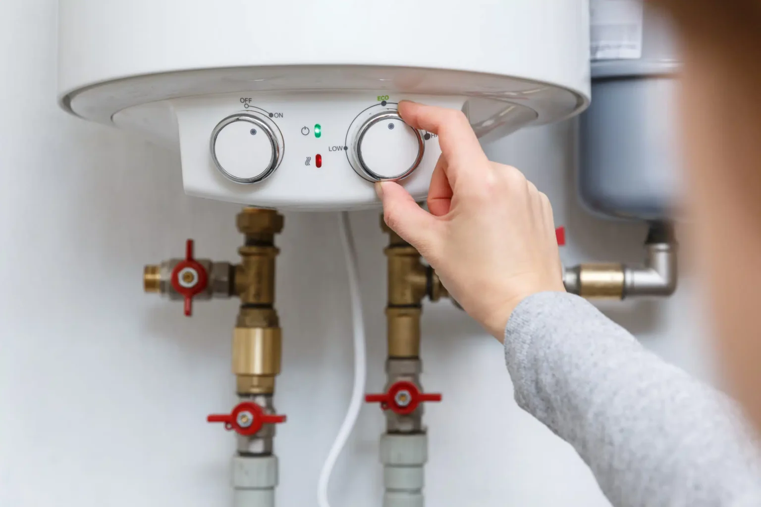 Homeowner adjusting the temperature controls on a water heater in Ontario